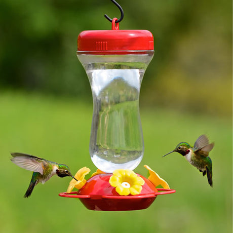 16 oz. Top Fill Hummer Feeder with clear glass reservoir and red plastic accents, featuring four yellow flower-shaped feeding ports and an easy-to-clean design.