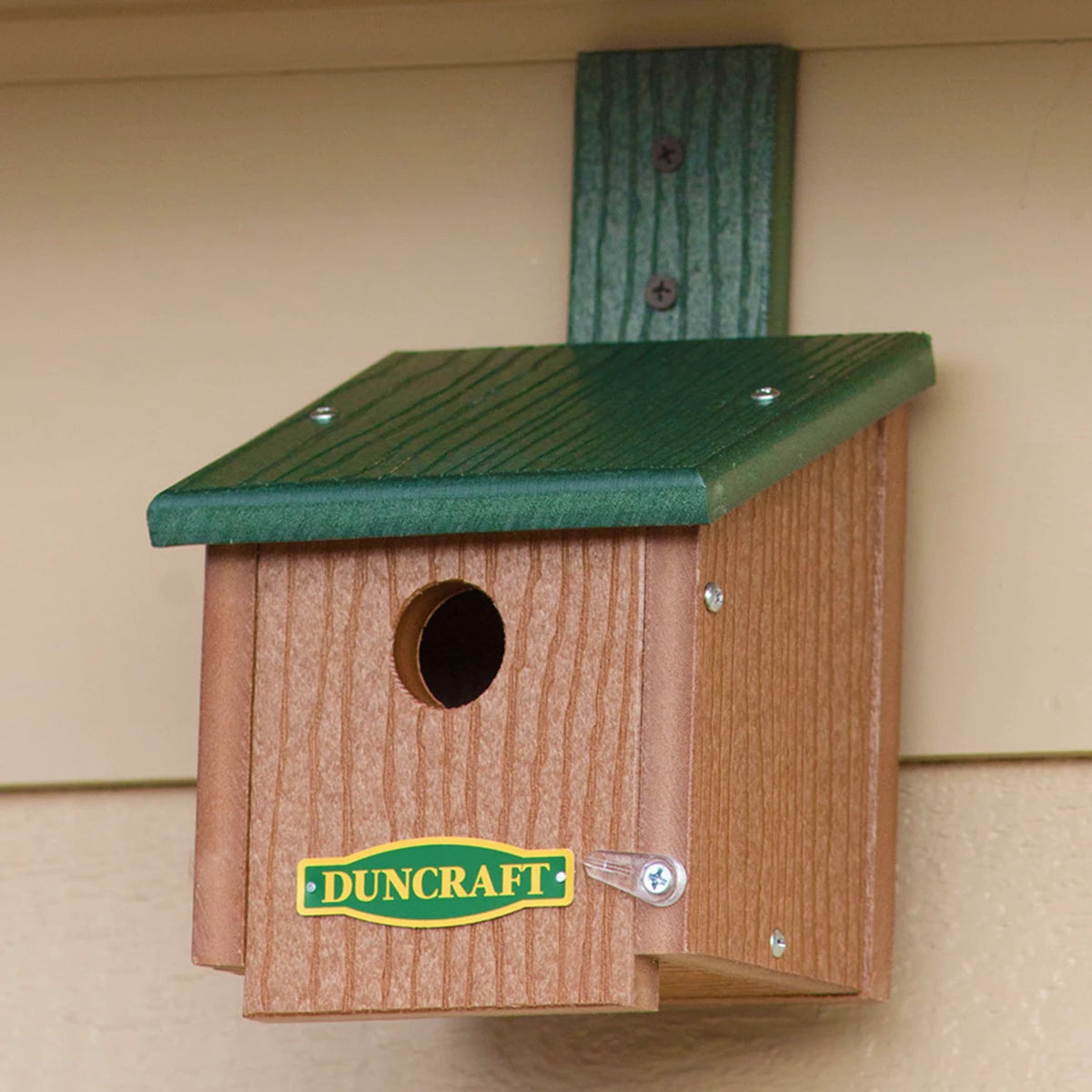 Duncraft Chickadee Roosting House with Swivel Mounting Bracket featuring a green slanted roof and round entrance, mounted on a structure.