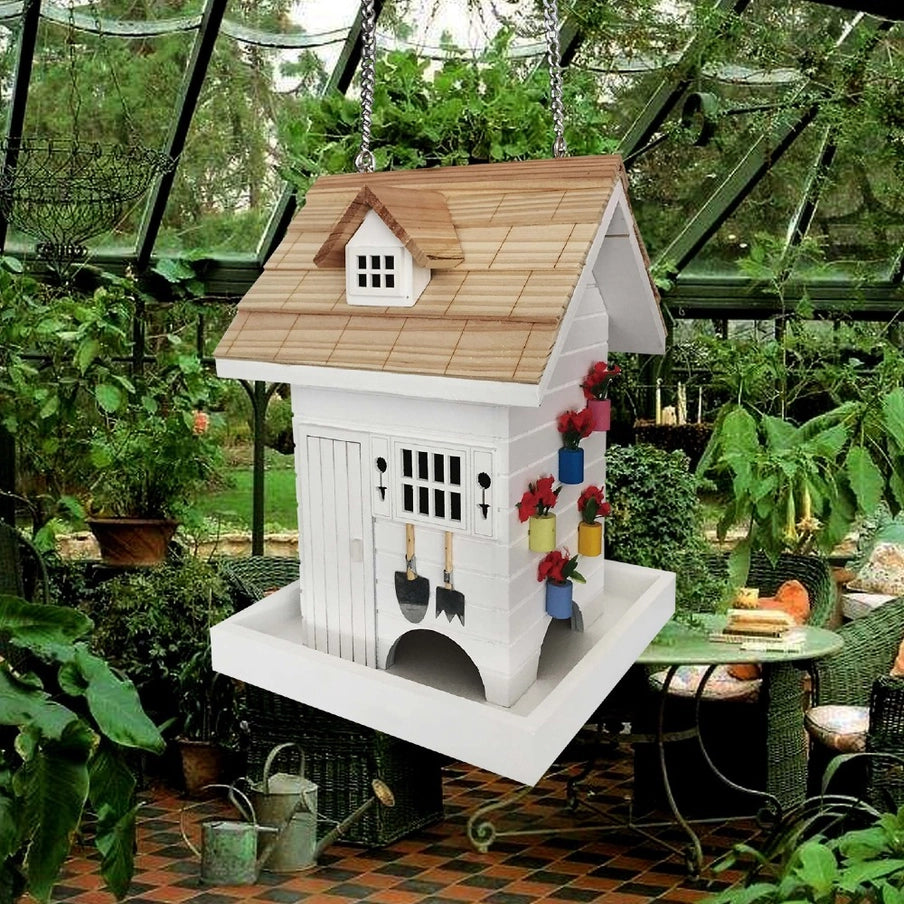 Potting Shed Bird Feeder in a garden setting, showcasing decorative potted plants, trellis, topiary cutouts, and garden tools, designed for easy bird feeding.