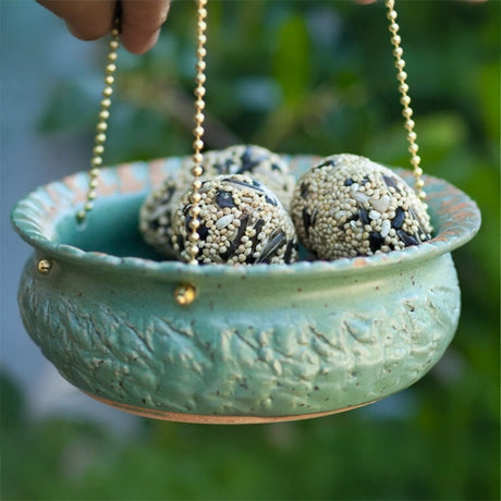 Bluebird Cafe Bird Feeder held in hand, featuring a glass dish filled with seeds, designed to attract birds.