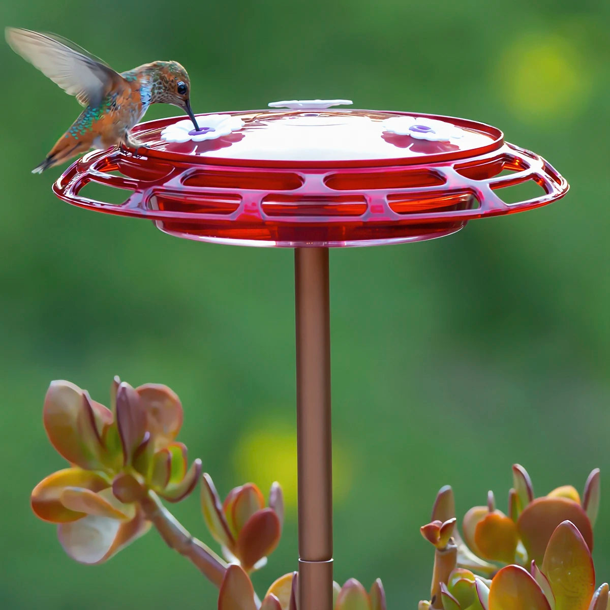 3-in-1 Hummingbird Feeder with red flower-shaped design, mounted on a pole, surrounded by succulents, offers three feeding stations and multiple mounting options.
