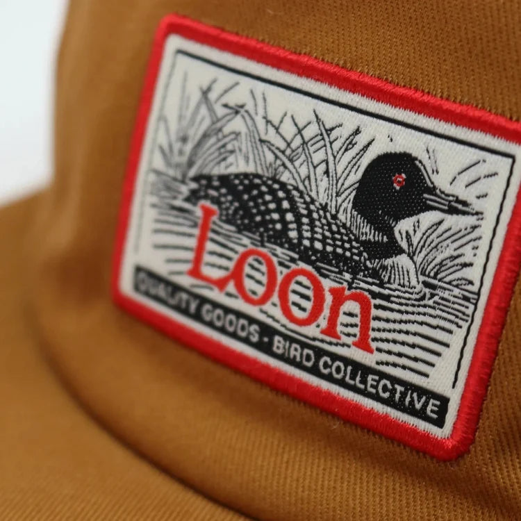 Close-up of the Loon Lake Camp Hat, featuring a loon illustration patch on a brown corduroy cap, perfect for birdwatching enthusiasts with an adjustable strap.
