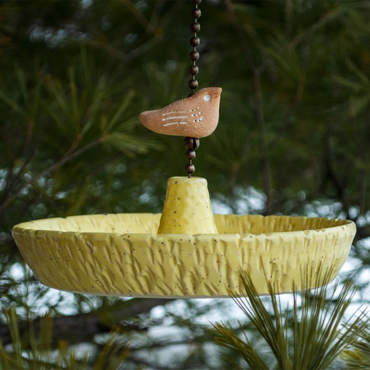 Platter Bird Feeder hanging from a tree, features a rough edge for perching. Handcrafted stoneware with brass chain, perfect for outdoor bird feeding.