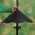 Person fitting an Extra Large Pole Baffle, Black, around a pole to deter squirrels, showcasing its scalloped-edge design and easy-lock feature.