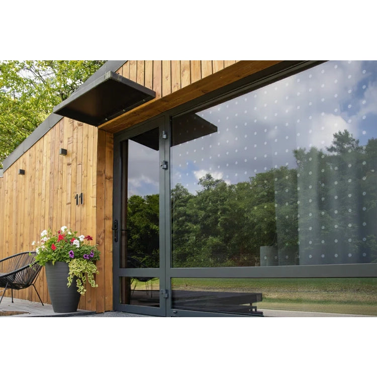 Modern wooden cabin with large glass door and potted plants on a patio