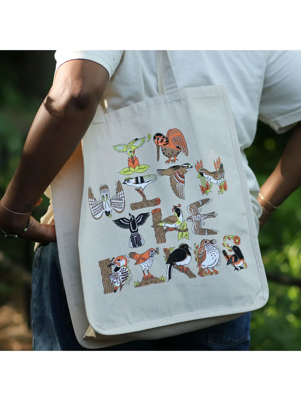Bird Collective I'm with the Birds Tote Bag featuring illustrations of various birds, worn by a person with a white shirt, showcasing its size and style.