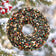 Birdseed wreath hanging from a snow-covered evergreen branch with red winter berries in a beautiful snowy backyard setting.