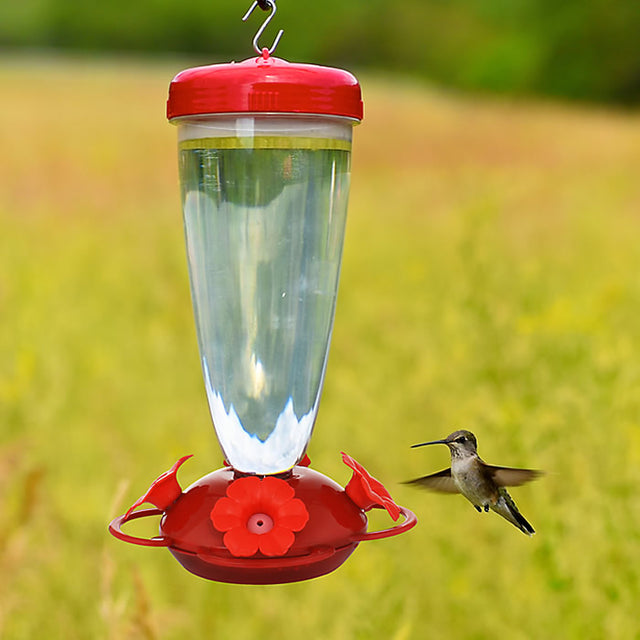 Top Fill Red Petunia Flower Hummingbird Feeder with clear plastic reservoir and petunia-shaped feeding ports, shown with a hummingbird feeding.