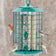 Duncraft Metal Safe Haven bird feeder with six feeding ports, outer caging, attached seed tray, and locking cap, attracting various birds while deterring larger ones and squirrels.