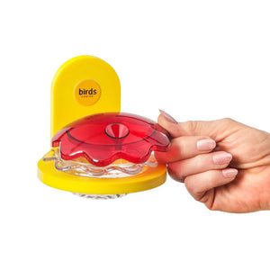 Hand holding Window Mount Hummingbird Feeder, Yellow, with visible suction cups and removable red lid for easy cleaning and refilling, designed to attract hummingbirds.