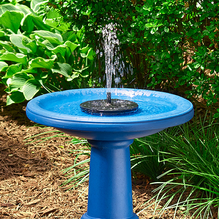 AquaNura Solar Mini Birdbath Insert in a garden, transforming a blue bird bath into a solar-powered fountain with gentle water flow.