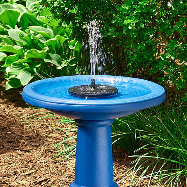 AquaNura Solar Mini Birdbath Insert in a garden, transforming a blue bird bath into a solar-powered fountain with gentle water flow.