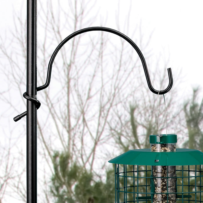 Quick Connect Heavy Duty Coil Arm, 12 inches, mounted on a pole, holding a green caged bird feeder designed for outdoor use, easily accommodates larger feeders.