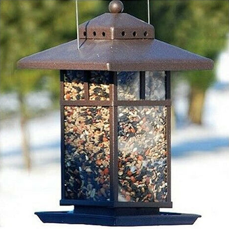 Metal Lantern Feeder filled with bird seed, featuring a metal design and tray for perching birds, suitable for outdoor use in any backyard.