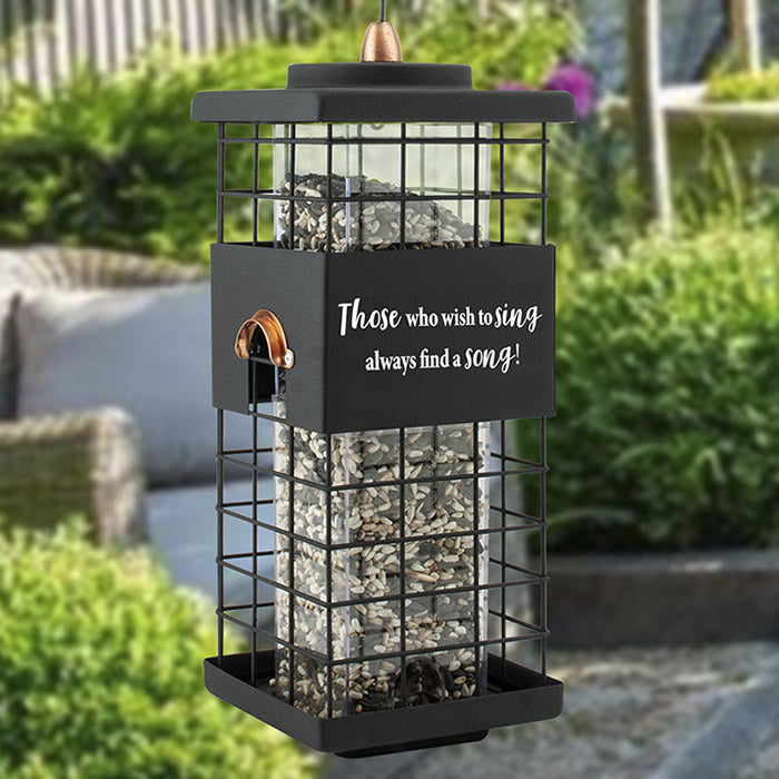 Modern Farmhouse Caged Tube Feeder with motivational quote, filled with rocks, featuring a metal grid, four feeding ports, and a wire hanger.