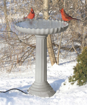 All Seasons Scalloped Bath in snow, with a bird perched on the basin, showcasing its stone-like, scalloped design and fluted pedestal.