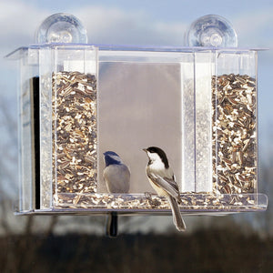 Duncraft Super Songbird Mirrored Feeder with two birds perched on its clear plastic hoppers, attached to a window via suction cups, designed for close-up birdwatching.