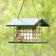 EZ Fill Deluxe Suet & Block Feeder with a green metal cage, suet-and-seed blocks, and a perched songbird, featuring a protective metal roof and hanging chain.