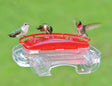 Aspects Jewel Box Hummingbird Feeder with multiple hummingbirds feeding at three raised ports on a transparent container attached to a window.