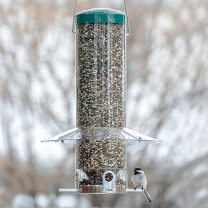 Large Classic Hanging Feeder with clear baffle, filled with birdseed, shelters a small bird perched on one of its four feeding ports.