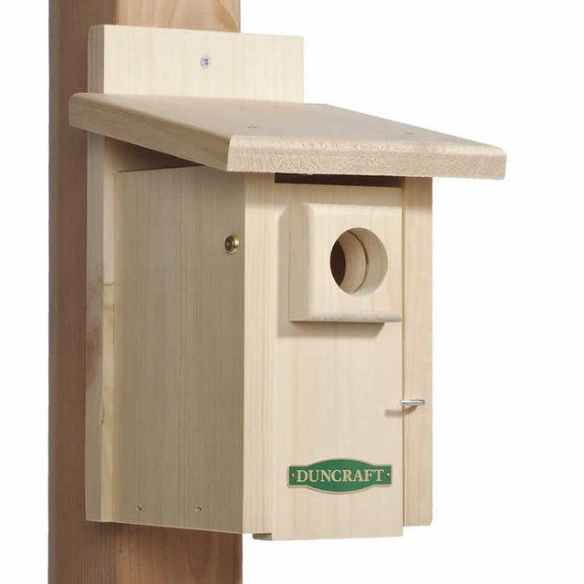 Duncraft Extreme Ventilated Bird House on a wooden post, featuring a 1-1/2 inch entry hole, overhanging roof, and built-in ventilation with stainless steel wire mesh.