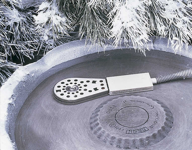 Deluxe Birdbath Heater on a concrete surface. Close-up of stainless steel housing and circular design, ideal for keeping birdbath water ice-free in cold weather.