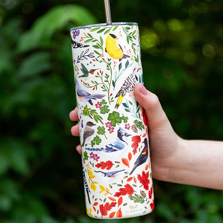 Hand holding the Wild Birds Tumbler, a 20 oz. matte-finished stainless steel container with a hand-painted bird design and stainless steel straw.