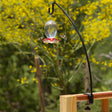 Clamp-On Deck Hook holding a hummingbird feeder, attached to a wooden deck railing with a curved arm for easy bird viewing.