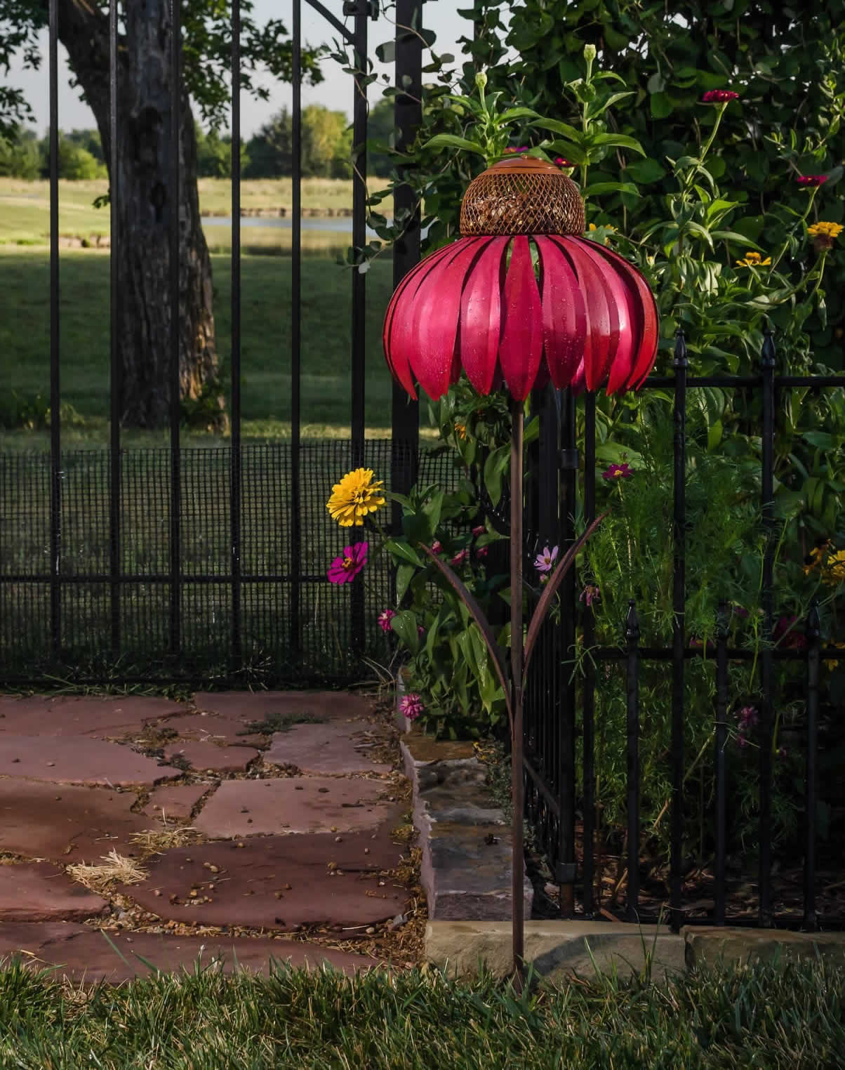 Sensation Pink Coneflower Bird Feeder in a garden setting, featuring durable galvanized steel and vibrant flower petals, designed to attract birds with its metal mesh.