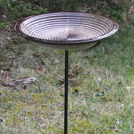 Circles Bird Bath Post in Sandy Granite on a sturdy pole, set in grass, with a 14-inch stoneware basin featuring concentric circles for bird perching.