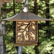 Pinecone Suet Feeder hanging from a tree, featuring a coppery leaf roof and decorative leaf vine. Durable metal design with secure leaf door in rear.