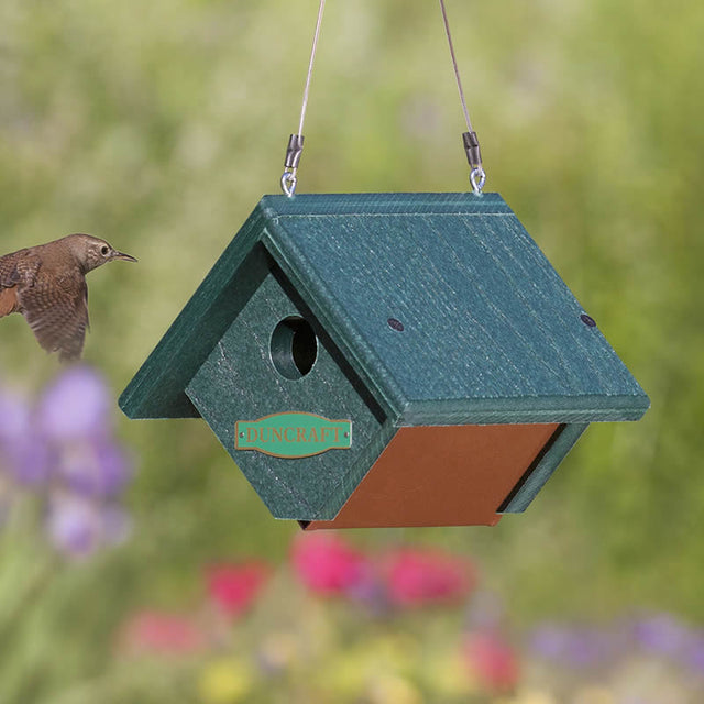 Duncraft Wren Bird House with a bird flying near it, featuring a wedge-shaped design, built-in ventilation, and a 1-1/8 inch entry hole.