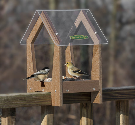 Duncraft Universal Deck Rail Feeder with clear plastic roof, mounted on a deck railing, attracting various birds. Durable, recycled plastic wood construction.