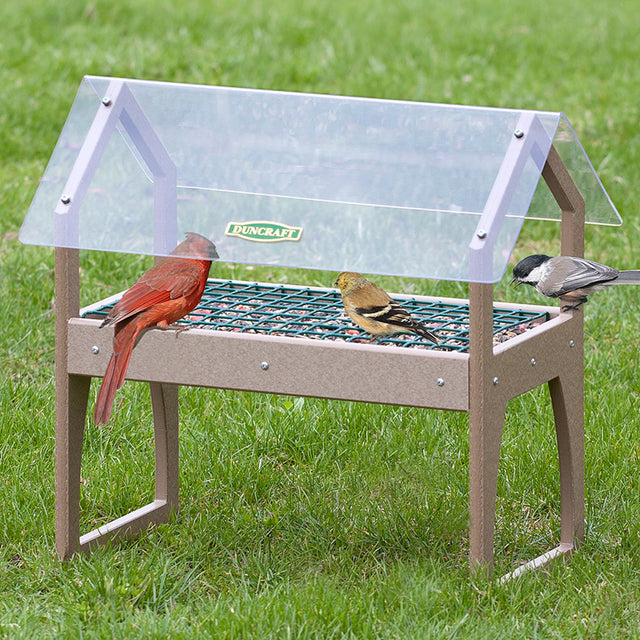 Duncraft Clearview Ground Platform Feeder with birds feeding, featuring a clear plastic roof, metal mesh tray, and easy access from all sides.