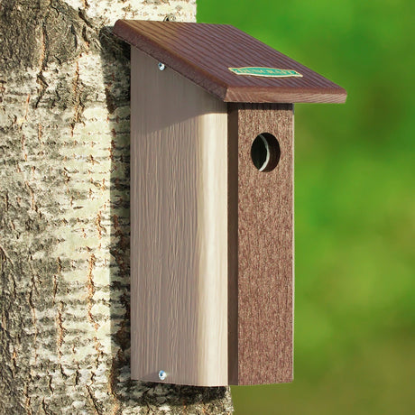 Downy Woodpecker Bird House mounted on a tree, featuring built-in predator guard and slim design, made from recycled materials.