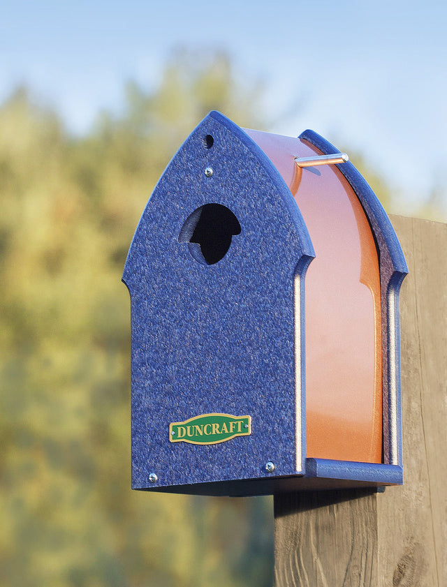 Duncraft Bluebird Enterprise Bird House on a wooden post with a unique entry hole and aluminum perching rod, offering ample ventilation and 360-degree view.