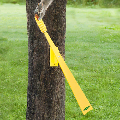 Weight Activated Squirrel Ride on a tree, featuring a yellow paddle and corn ear, challenging squirrels with a seesaw motion to reach their food.