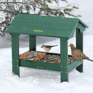 Duncraft Covered Ground Platform Feeder with birds on it in snowy outdoor setting, showcasing its vaulted cathedral ceiling and metal mesh flooring for easy viewing and drainage.