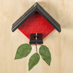 Duncraft Little Red Hummingbird House with branch and leaves for nesting. Features two metal posts for nest support, ideal for mounting under eaves.