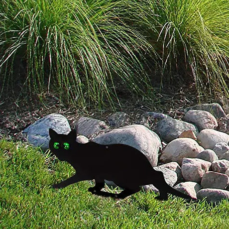 Garden Scare Cats with Reflective Eyes set amidst grass, designed to deter pests with lifelike features, enhancing garden protection naturally.