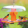 Duncraft Deluxe Oriole Jelly Feeder with weather dome, stocked with oranges and jelly, attracting two male and one female oriole in a garden setting.