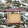 Duncraft 4-Sided Free-Flowing Hopper Feeder with songbirds perched, showcasing its large seed capacity and multi-sided feeding tray amidst snow-dusted evergreens.