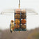 Duncraft Deluxe Seed & Suet Ball Feeder: Cylindrical wire cage with rain dome, hosting a woodpecker on seed balls. Features tail prop areas for balanced feeding.
