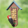 Duncraft Double Sided Woodpecker Feeder with wire mesh, woodpecker clinging, tail prop area, in a green backyard, designed for easy feeding and refills.