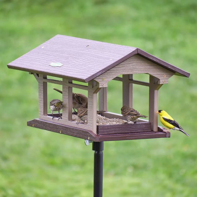 Duncraft Covered Bridge Feeder with Pole & Twister, featuring birds feeding from all sides on a durable platform with built-in perches and drainage.