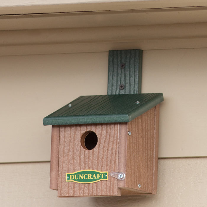 Duncraft Chickadee Roosting House with Swivel Mounting Bracket, featuring a green roof and 1-1/8 inch entry hole, mounted on a wall.