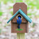 Duncraft Bird-Safe® Out of Reach Bird House with teal roof, bluebird at entrance, predator guard, metal portal, and easy-clean front panel.