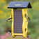 Duncraft Classic Wave Nyjer® Feeder with yellow frame, wire mesh, and four metal perches. Features three finches and one chickadee feeding.