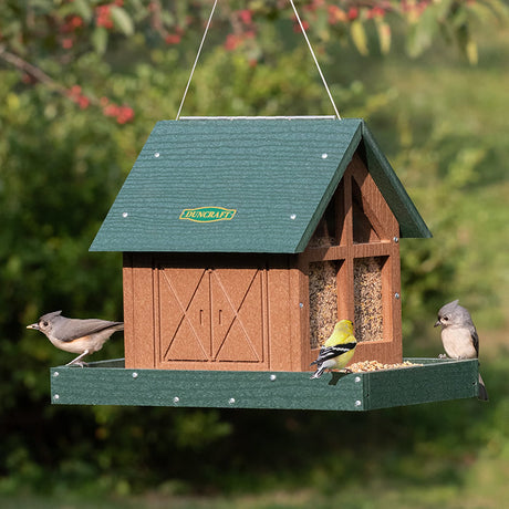 Duncraft Country Barn Feeder with two feeding trays, plastic panel windows, and metal mesh drainage, accommodating cardinals and large birds. Includes cable hanger for outdoor use.