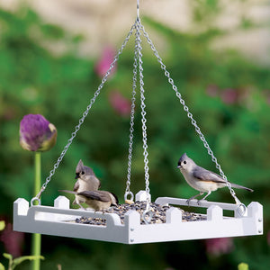 Duncraft White Picket Fence Platform Feeder with birds perched on it, featuring a durable white design and hanging chain with metal mesh drainage.